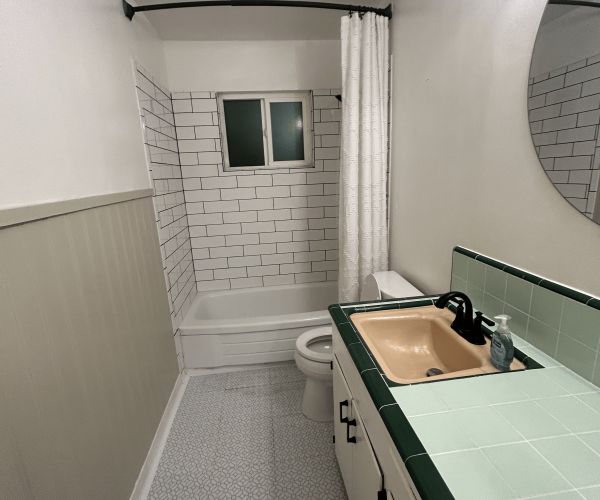 Before: Uneven tile walls, window leaks, subfloor damage, 1950s vanity.